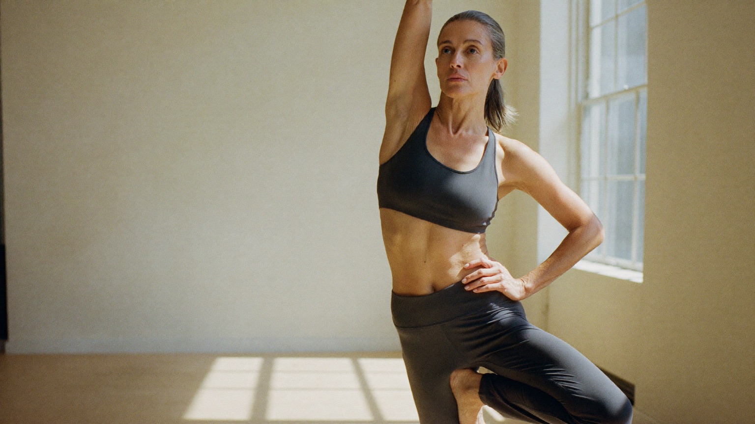 Donna adulta in posizione di yoga in uno studio luminoso che ha fatto mastoplastica con protesi piccole